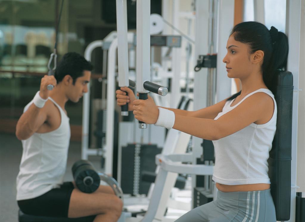 فندق ذا أوبروي بنجلور بنغالور المظهر الخارجي الصورة A woman using a lat pulldown machine